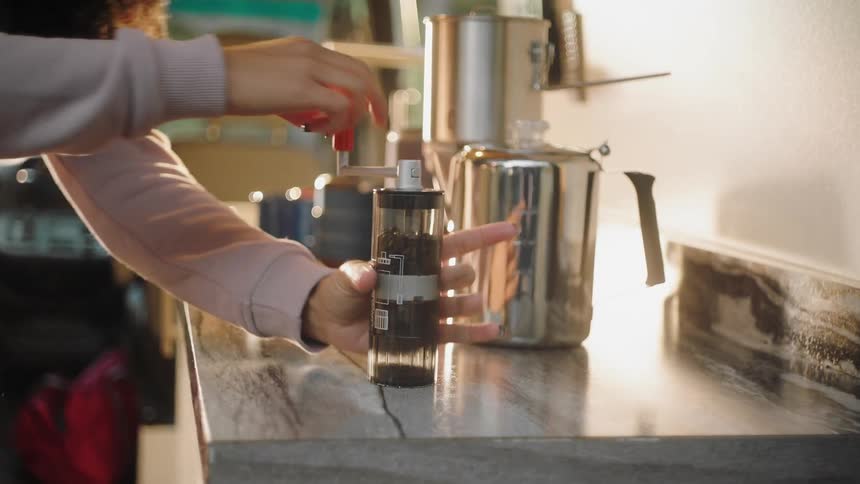 A woman with a sweater in a vehicle grinding coffee beans on a table
