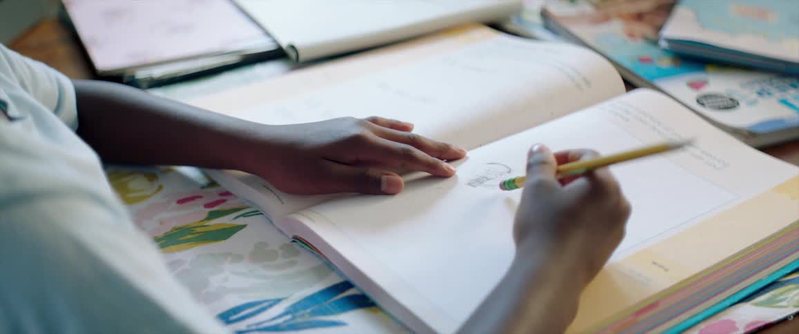 A student studying at a table with an open book and pencil