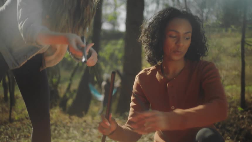 Two women that are assembling a tent outdoors