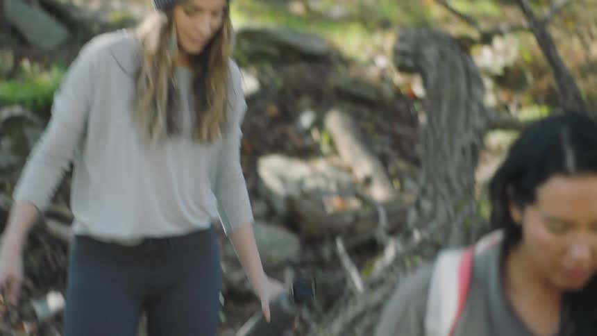 Female friends hiking across a small creek in the woods