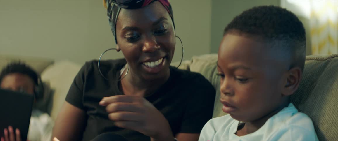 Mother helping son with homework while sitting in a couch at home