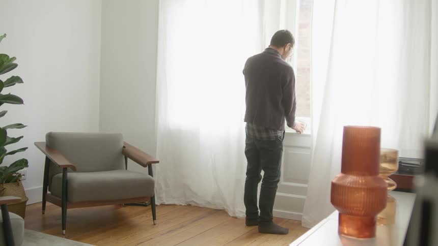 A man is drinking from a mug and talking on his cell phone