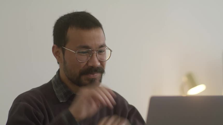 A man smiling and blowing kisses while video chatting on a laptop