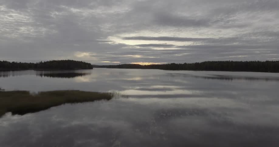 Moving over a lake with reflective water at sunset
