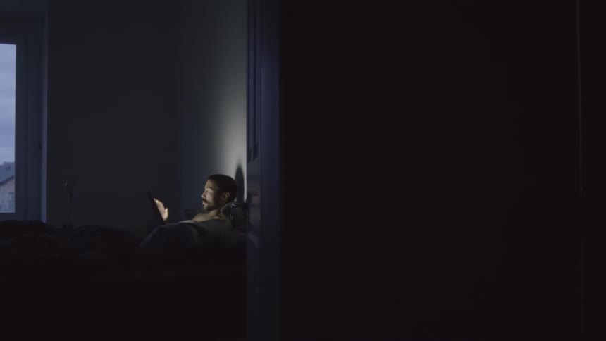 A man is sitting indoors and using a laptop