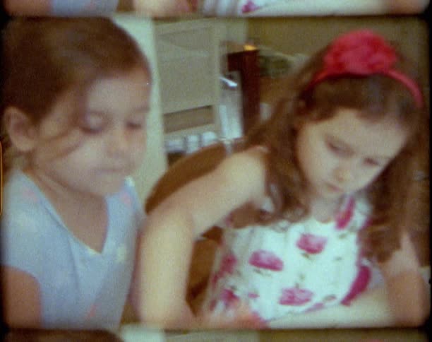 A vintage film of two young girls at home eating and stirring in a bowl
