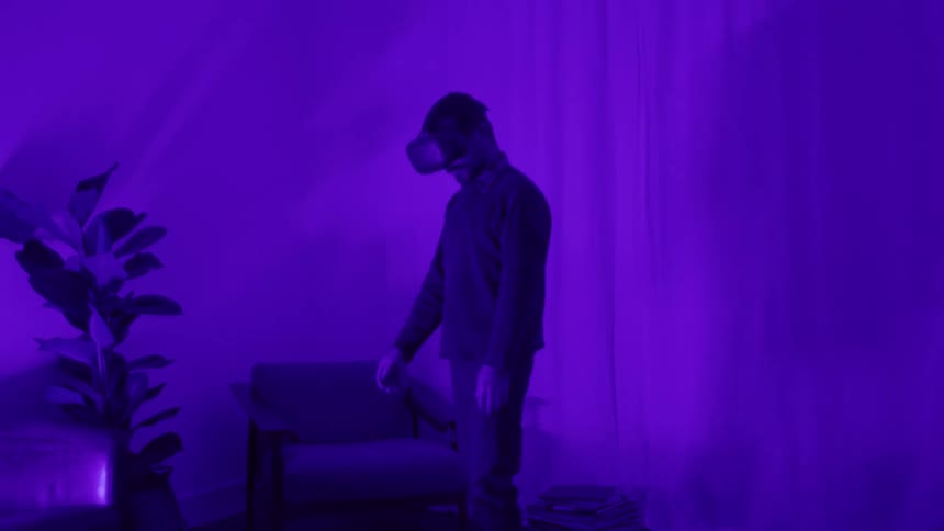 A man at home puts virtual reality goggles on and prepares to golf