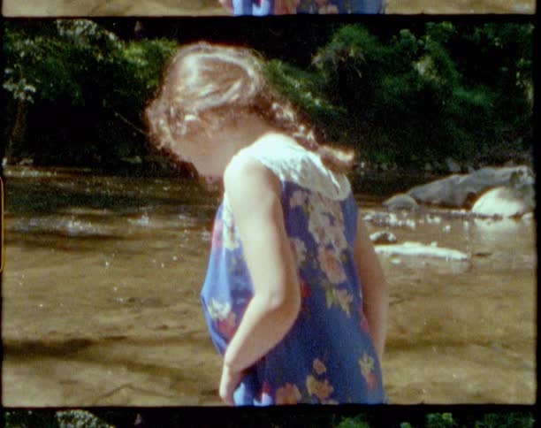 Two young girls are standing in very shallow water of a stream