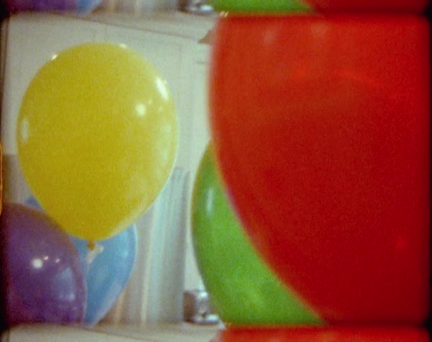 A kitchen with balloons with a woman standing by a counter in the background