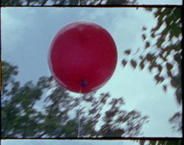 Red balloon on a string swaying back and forth outdoors
