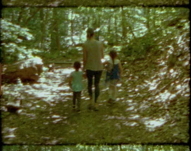 Mother and young daughters walking on a trail in the woods