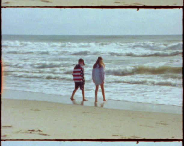 Two kids that are walking at the beach