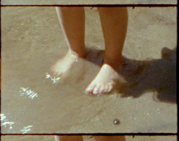 A person walking and splashing in water and sand