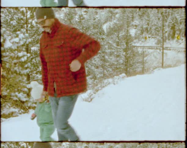 Vintage footage of a father holding his daughters hand as they walk through the snow