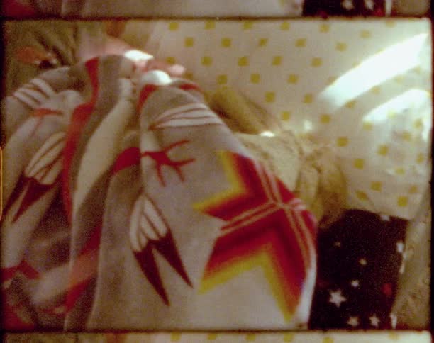 A little girl inside a crib hides under the blanket playing a game