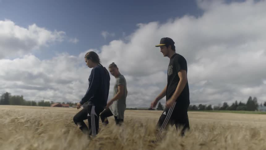 Three people walking through a field on a cloudy day