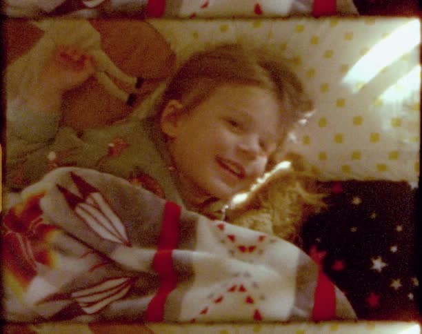 Vintage footage of a little smiling as she lies in bed