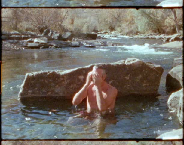 A man that is dunking his head in a river