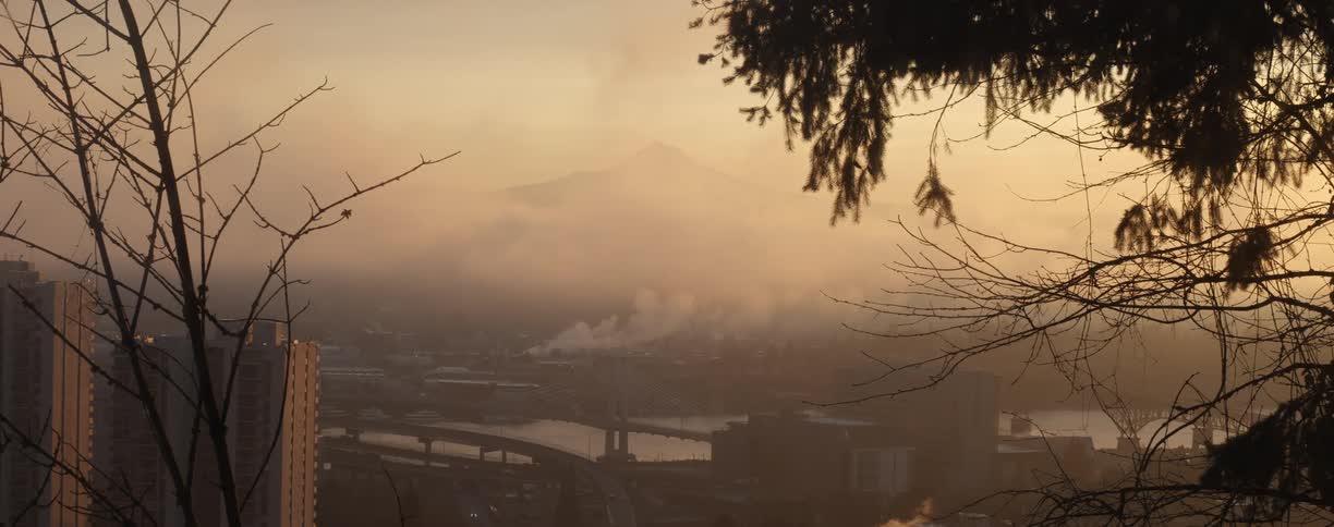 A landscape view of smoke billowing from buildings behind a river
