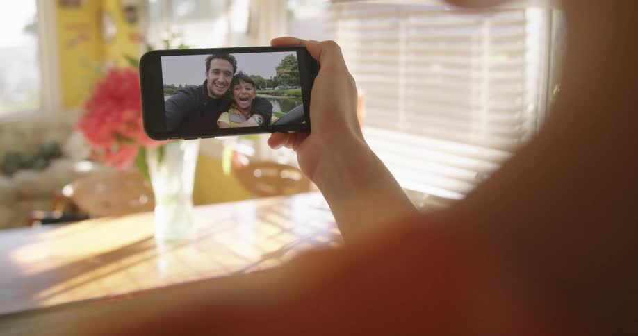 A woman at home chats with her husband and son on her cell phone as they ride in a boat