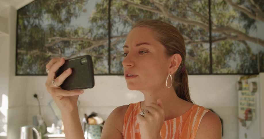 A woman waves and blows an air kiss during a video call at home on her smartphone