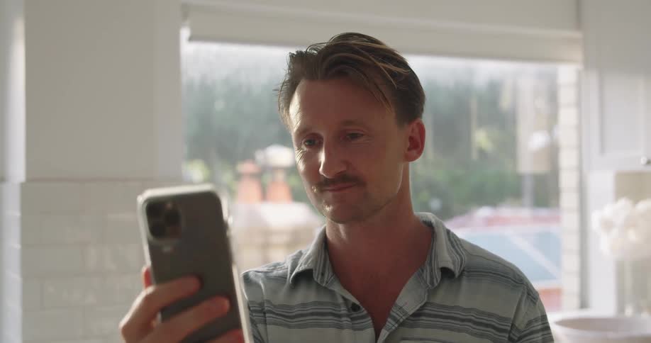 Man standing in a room ends a video call on his smartphone