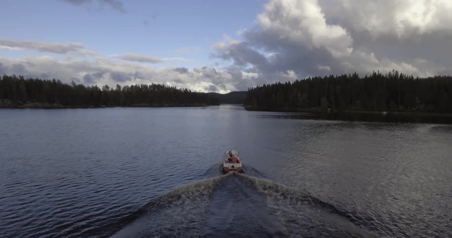A person crosses a lake in a motor boat