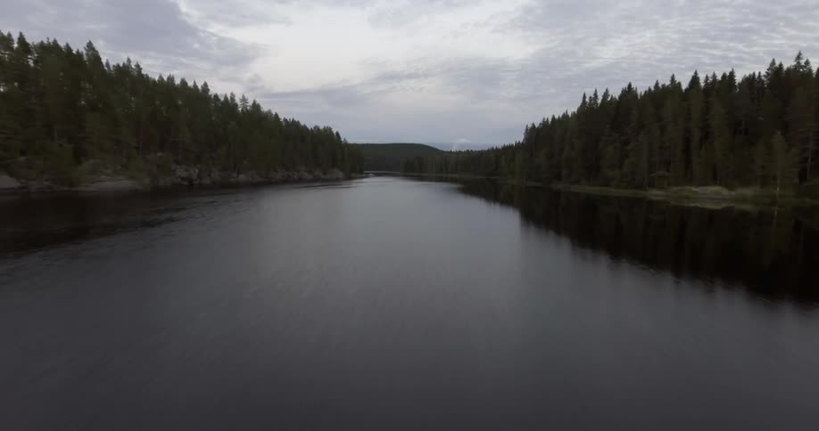 A calm river surrounded by forests on both sides on an overcast day