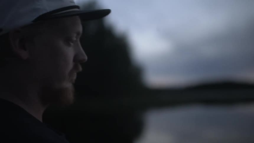 A man fishes in a lake at sunset