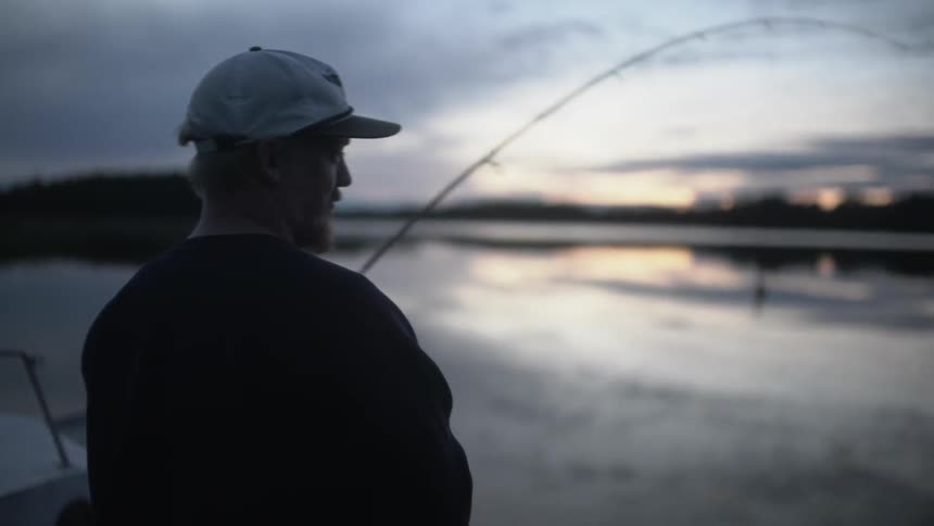 A man wearing a cap fishing at dawn