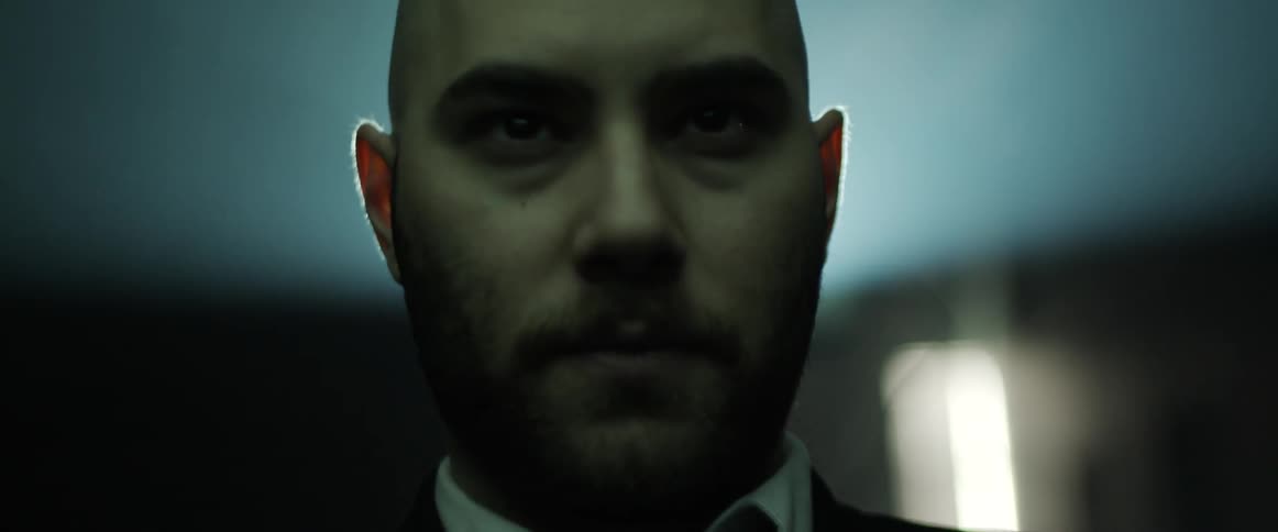 A man stands in the middle of a room looking in the distance and not blinking