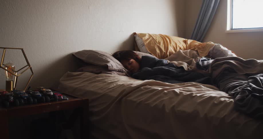 A person in a bedroom sleeping on a bed with pillows