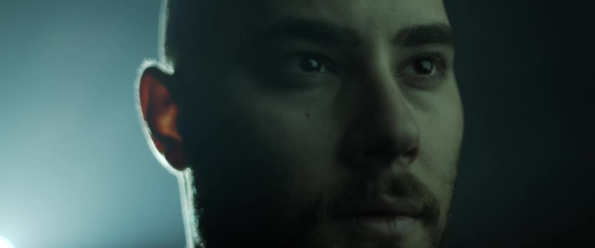 Man backlit by bright light stares in shadowy room