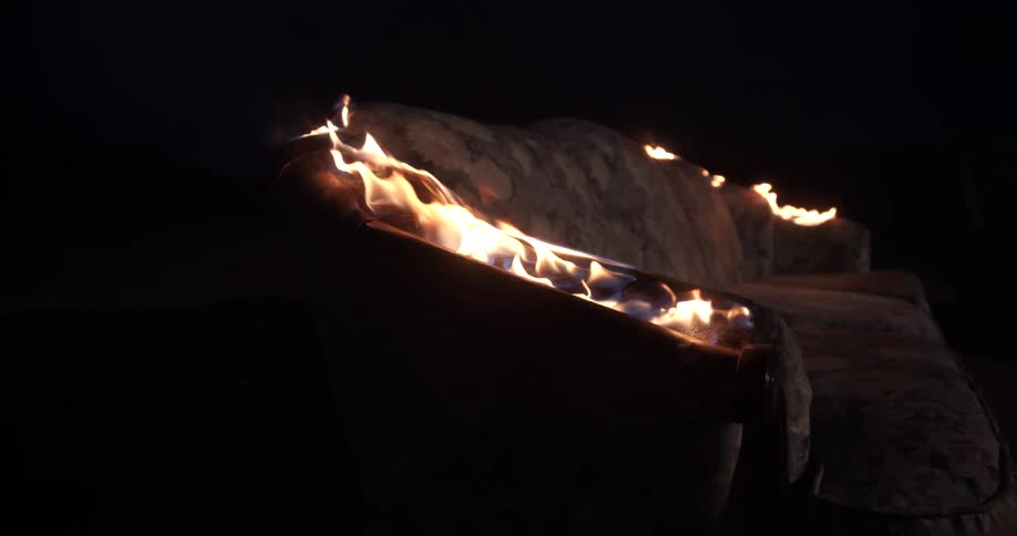 A couch is in flames burning in the darkness
