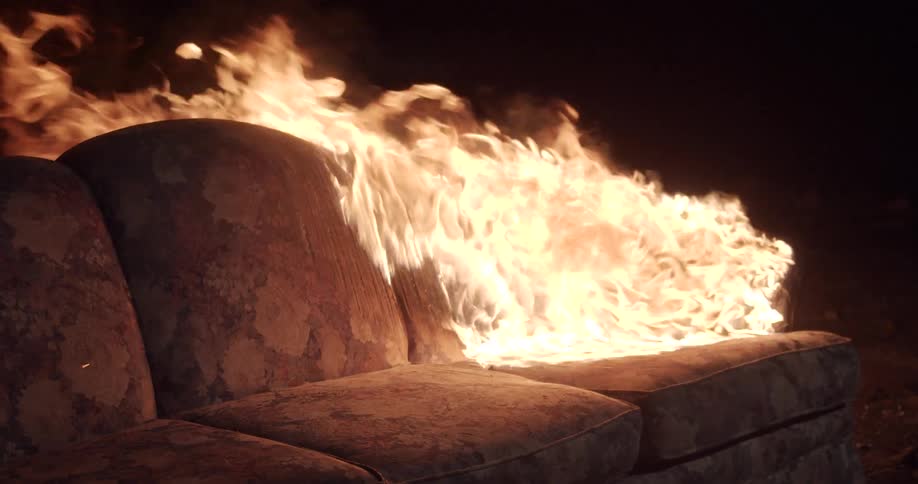 A couch on fire burning with flames and smoke