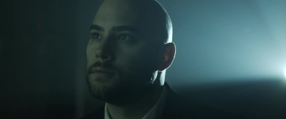 A man is sitting in a dark room indoors