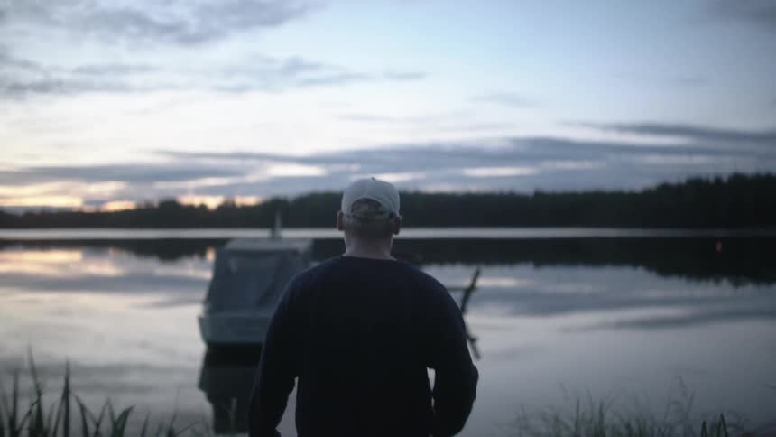 A man is walking with a fishing pole towards the water