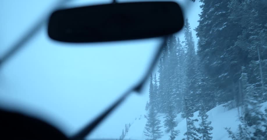A car driving through a snow storm with wipers on