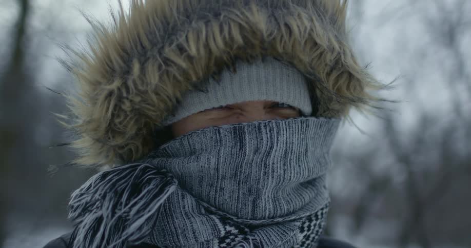 A person is bundled up in a scarf and large coat