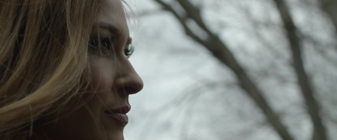 A woman with makeup with a tree the sky and clouds in the background
