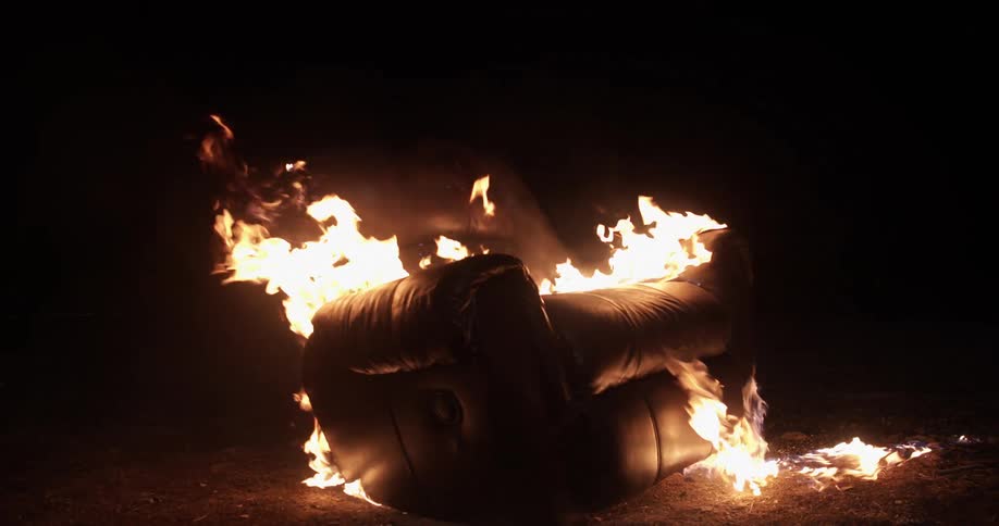 A couch on fire burning with flames and smoke