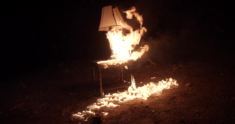 A lamp and a nightstand burning on fire with smoke