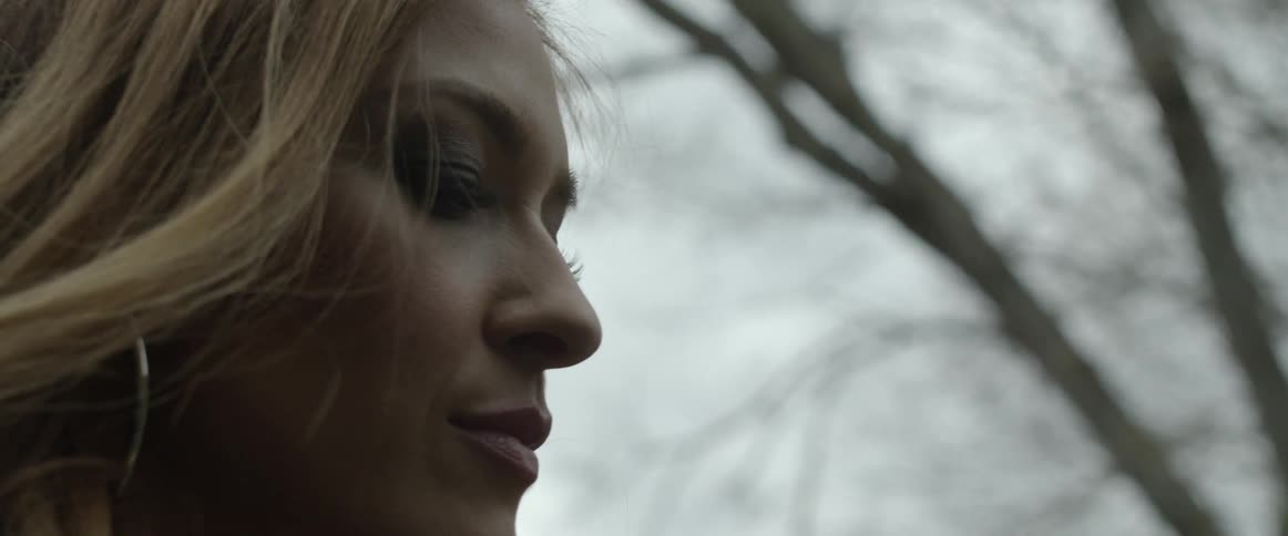 A woman with makeup with a tree the sky and clouds in the background