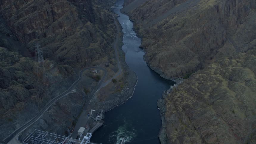 Tilting down from a beautiful mountain river valley to reveal a dam and hydroelectric power station