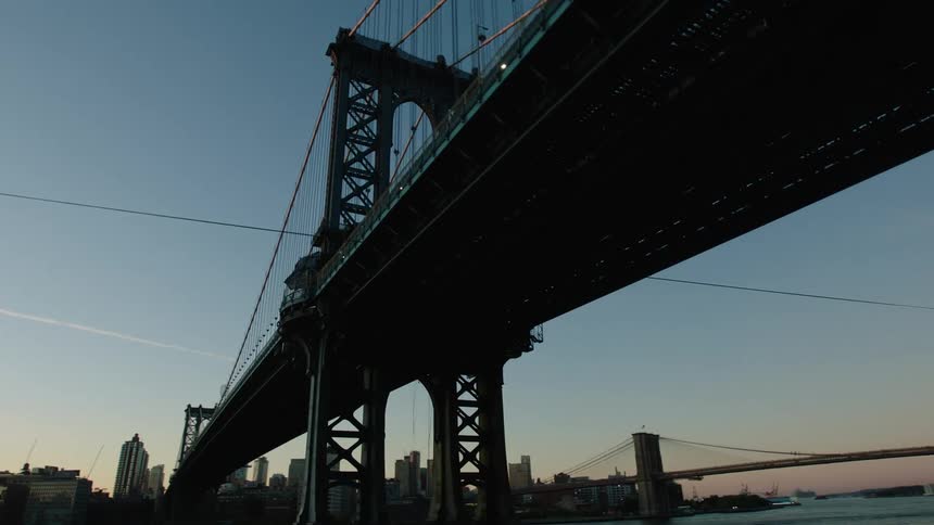 A bridge spans a waterway in a metropolis in the evening