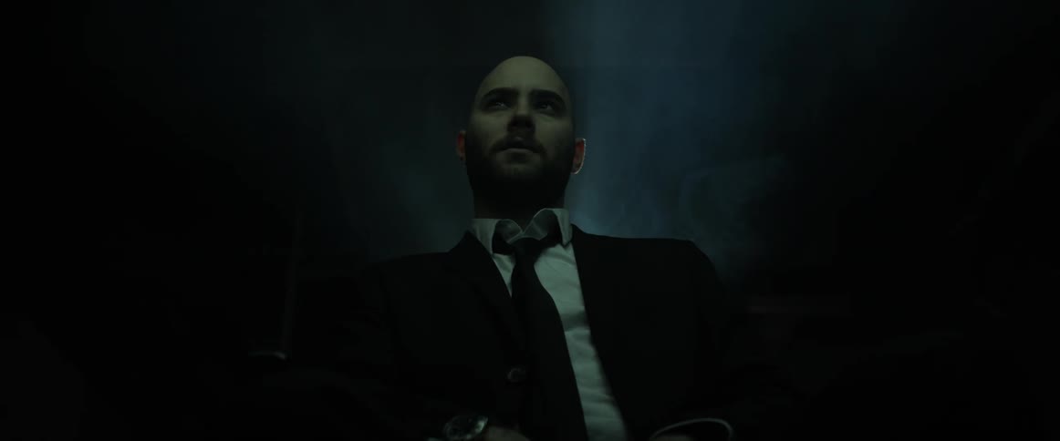 A man is watching something in a dark room