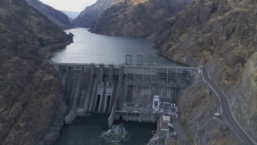 A large reservoir stands behind a tall dam in a river gorge