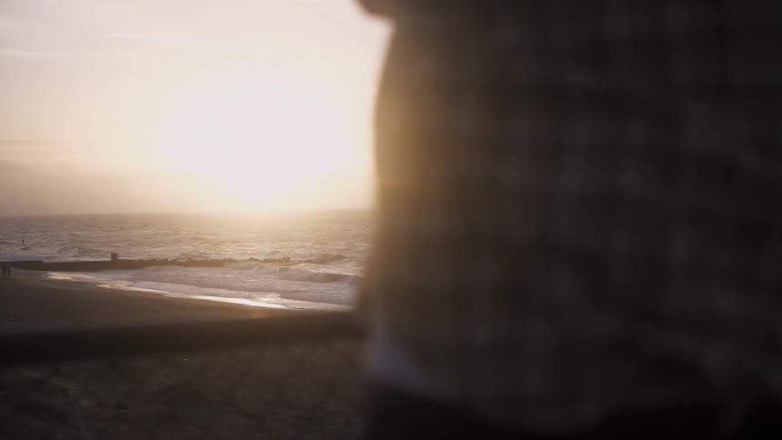 A person is watching the sun set over the ocean
