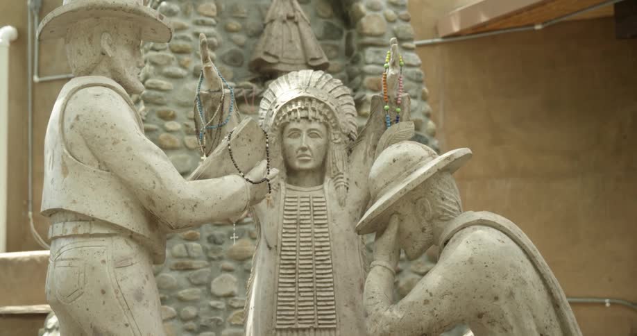 Necklaces hang from the hands of a sculpture of three people