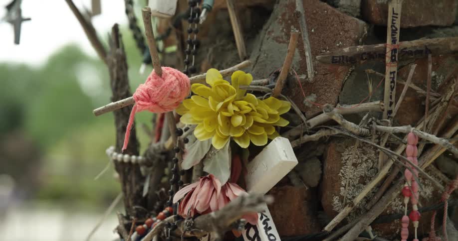 Flowers beads and crosses adorn a stone and brick section of wall